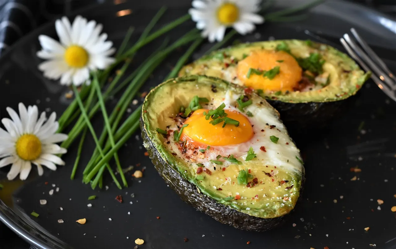 Eggs baked in avocado halves on a dark plate — a breakfast that clears the 25-gram protein threshold